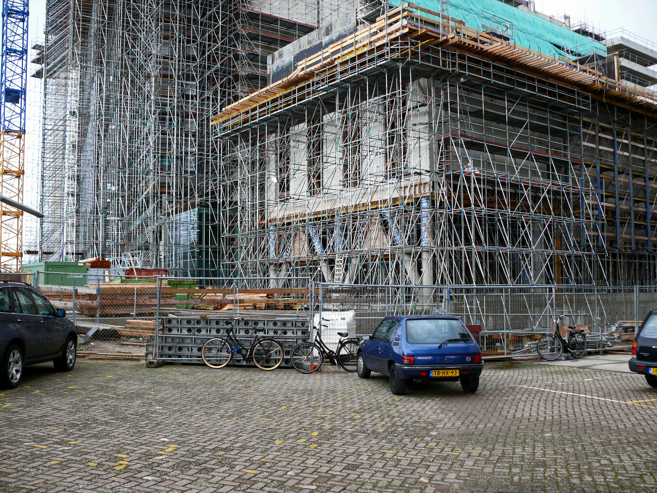 A building under renovation wrapped in scaffolding on a cobbled street